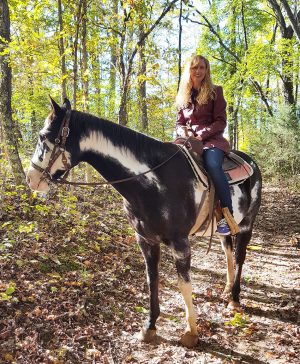 Jennifer Hudson Taylor horseback riding in wooded mountains